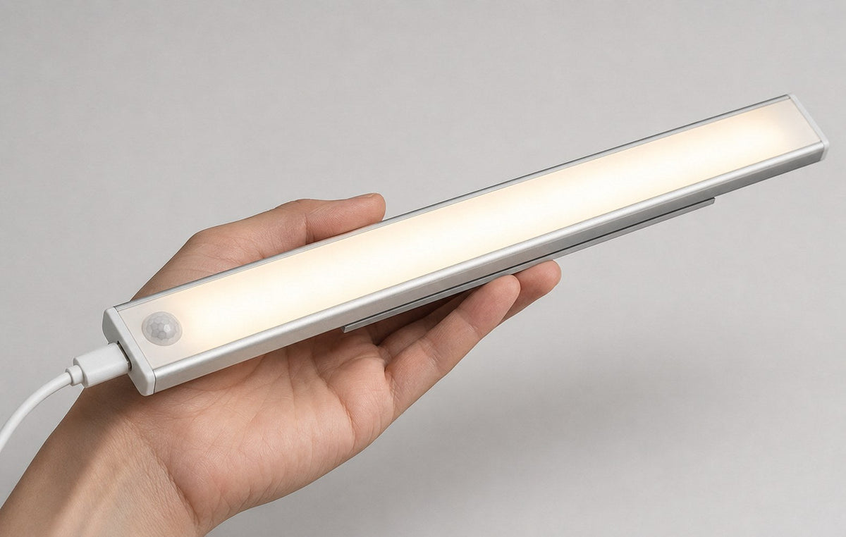 Dwellio LED bar held in a hand with USB-C charging cable attached, showing its compact size